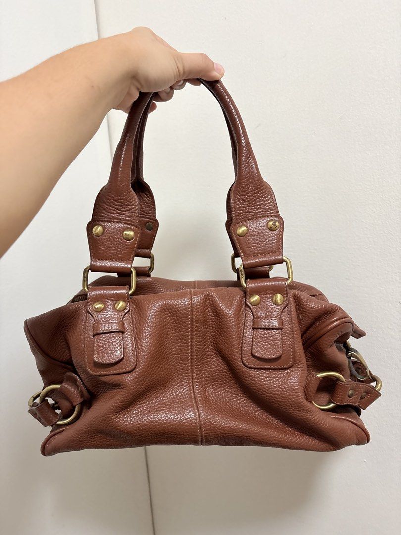 Brown Leather Shoulder Bag (Category: Shoulder Bags) located in Cabuyao City. Submitted by mhd.i (Listing ID 1468877075, Image 1). Description: Condition: Good preloved condition with signs of use. DM for more photos! Hardware: Features brass-tone metal accents. Please note there is noticeable tarnishing, color fading, and minor green oxidation on the rivets and buckles as shown in the photos. The zippers are fully functional. Leather: Soft, pebb