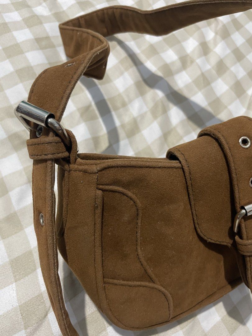 Brown Suede Shoulder Bag Y2K Buckle Bag (Category: Shoulder Bags) located in Manila. Submitted by airaaaac (Listing ID 1468809362, Image 3). Description: - Material: Brown faux suede with chic contrast stitching - Hardware: Silver-tone metal details - Closure: Front flap with magnetic snap button plus secure zippered main compartment - Straps: Adjustable side buckles with metal eyelets - Interior: Lined with clean black fabric - Condition: Clean 