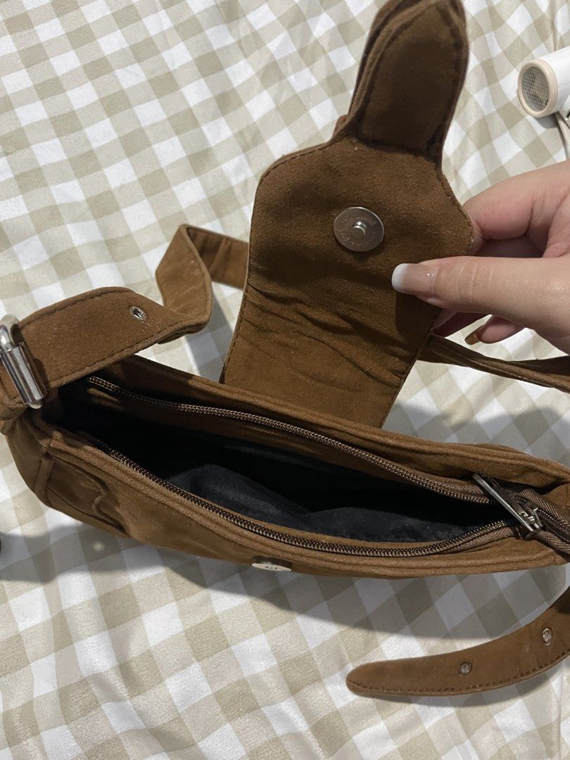 Brown Suede Shoulder Bag Y2K Buckle Bag (Category: Shoulder Bags) located in Manila. Submitted by airaaaac (Listing ID 1468809362, Image 2). Description: - Material: Brown faux suede with chic contrast stitching - Hardware: Silver-tone metal details - Closure: Front flap with magnetic snap button plus secure zippered main compartment - Straps: Adjustable side buckles with metal eyelets - Interior: Lined with clean black fabric - Condition: Clean 