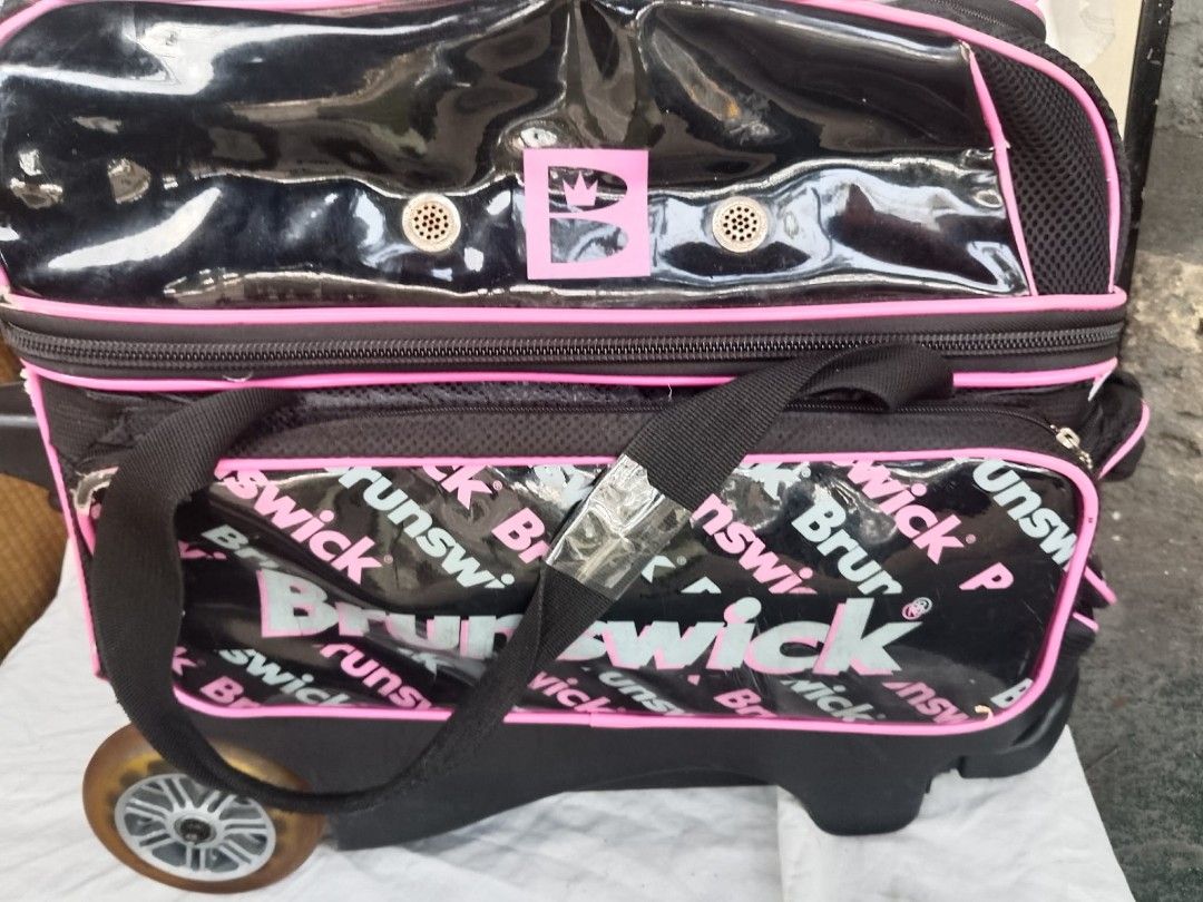 Brunswick Rolling Bowling Bag Black Pink (Category: Billiards and Bowling) located in Quezon City. Submitted by jpnvintageonline (Listing ID 1468832970, Image 1). Description: - Authentic Brunswick rolling bowling bag in stylish black and pink - Glossy front panel with repeated logo print - Equipped with an extendable handle, sturdy wheels, and carrying strap - Smooth-working zippers with plenty of storage space for gear and bowling shoes - Shows