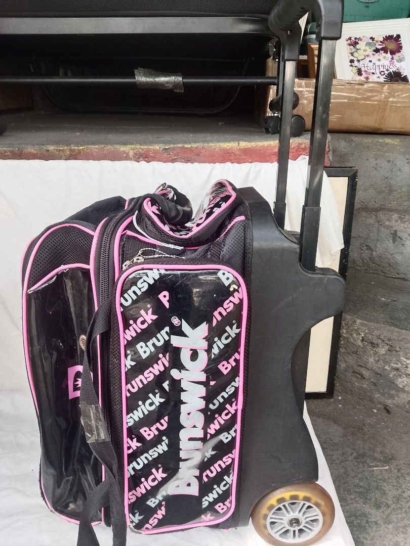 Brunswick Rolling Bowling Bag Black Pink (Category: Billiards and Bowling) located in Quezon City. Submitted by jpnvintageonline (Listing ID 1468832970, Image 2). Description: - Authentic Brunswick rolling bowling bag in stylish black and pink - Glossy front panel with repeated logo print - Equipped with an extendable handle, sturdy wheels, and carrying strap - Smooth-working zippers with plenty of storage space for gear and bowling shoes - Shows