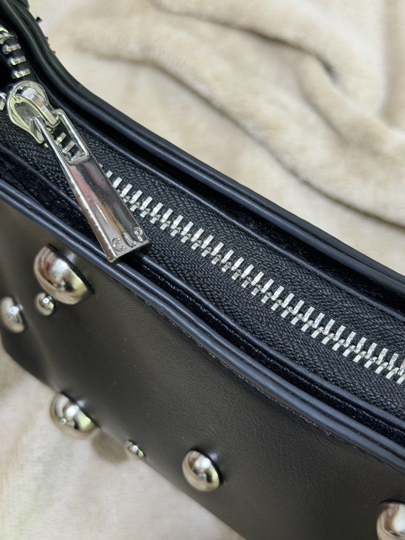 Calliope Black Studded Shoulder Bag (Category: Shoulder Bags) located in Manila. Submitted by declutterwtmaan (Listing ID 1468746633, Image 2). Description: - Brand: Calliope - Material: Black faux leather - Details: Silver-tone studs and grommets on the front - Closure: Zip top with metal pull - Interior: Clean black fabric lining with branded tag - Style: Compact, everyday shoulder bag USED ONCE.