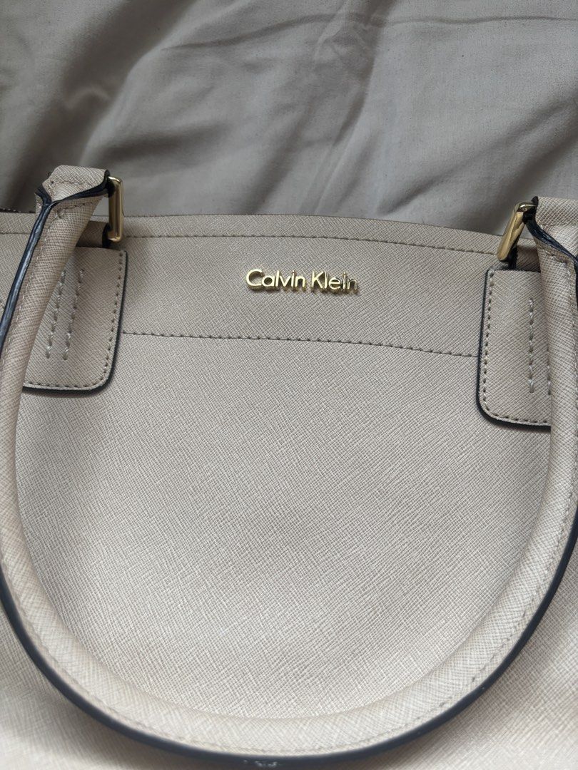 Calvin Klein beige structured tote bag (Category: Tote Bags) located in Taguig. Submitted by arcjvcs (Listing ID 1468818523, Image 3). Description: - Brand: Calvin Klein - Color: Classic beige - Material: Durable Saffiano-texture - Hardware: Gold-tone - Closure: Top zip - Handles: Twin top handles - Interior: Dark branded fabric lining.