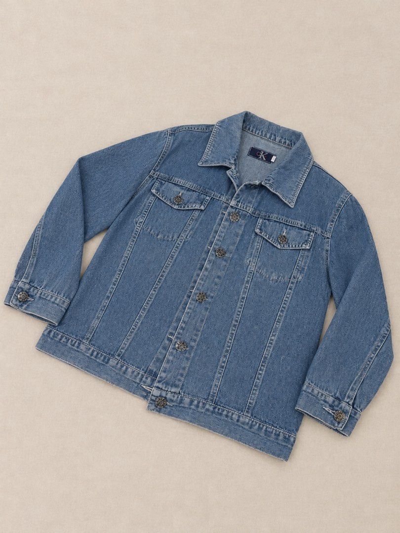 Calvin Klein Blue Denim Jacket (Category: Coats, Jackets and Outerwear) located in Manila. Submitted by lexiandco.ph (Listing ID 1468722141, Image 2). Description: - Brand: Calvin Klein - Color: Classic Blue - Material: Durable denim - Features: Metal front button closure, two chest flap pockets, button cuffs, and structured collar - Details: Contrast stitching throughout - Fit: Easy layering piece for cooler weather - Condition: Pre-loved, well-