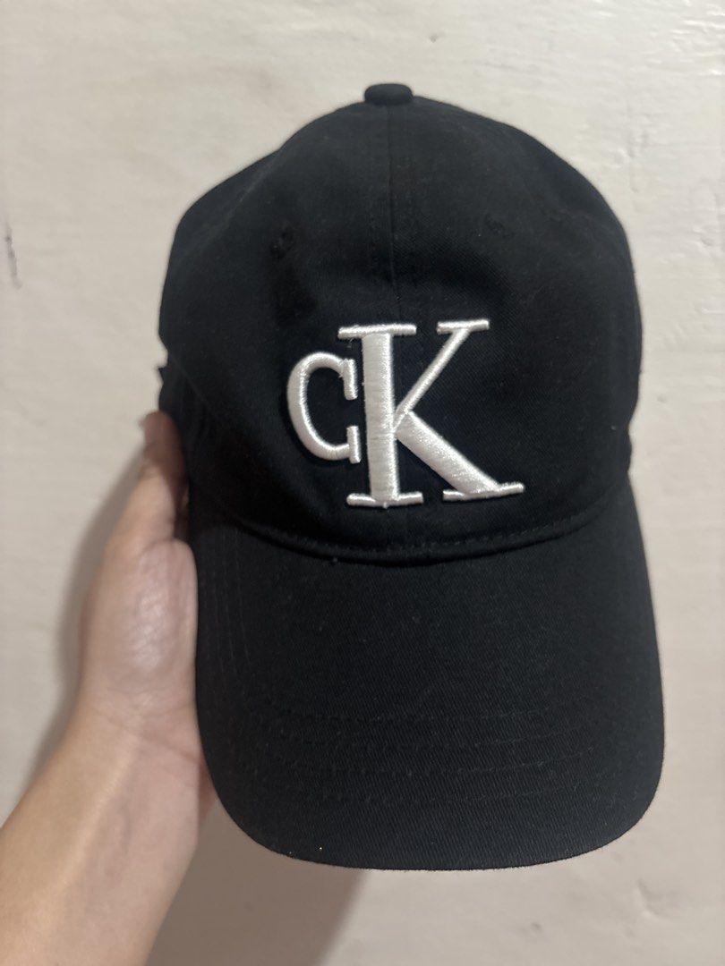 Calvin Klein Jeans Black Baseball Cap (Category: Caps & Hats) located in Taguig. Submitted by fatzy24 (Listing ID 1468920840, Image 1). Description: Black Calvin Klein Jeans cap with embroidered white CK logo on the front. Made of 100% cotton, 58cm sizing. Silver-tone metal buckle closure stamped with CK branding at the back. Interior tags intact showing fabrication details from Cambodia..