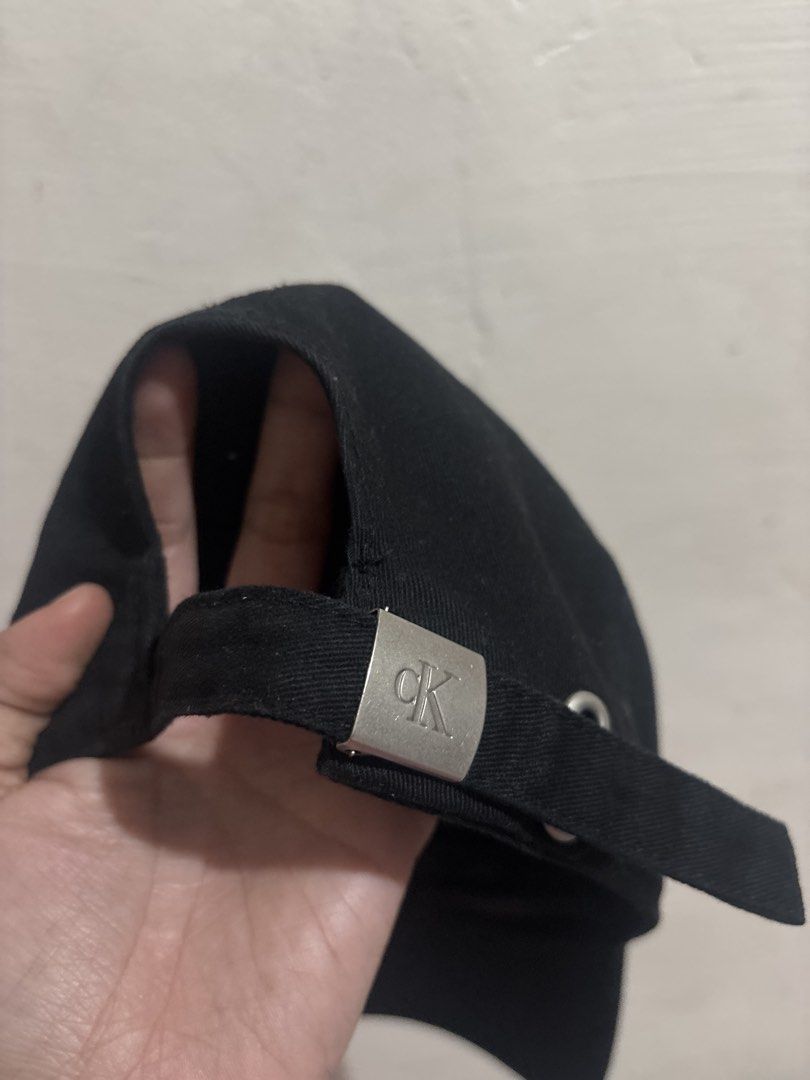 Calvin Klein Jeans Black Baseball Cap (Category: Caps & Hats) located in Taguig. Submitted by fatzy24 (Listing ID 1468920840, Image 2). Description: Black Calvin Klein Jeans cap with embroidered white CK logo on the front. Made of 100% cotton, 58cm sizing. Silver-tone metal buckle closure stamped with CK branding at the back. Interior tags intact showing fabrication details from Cambodia..