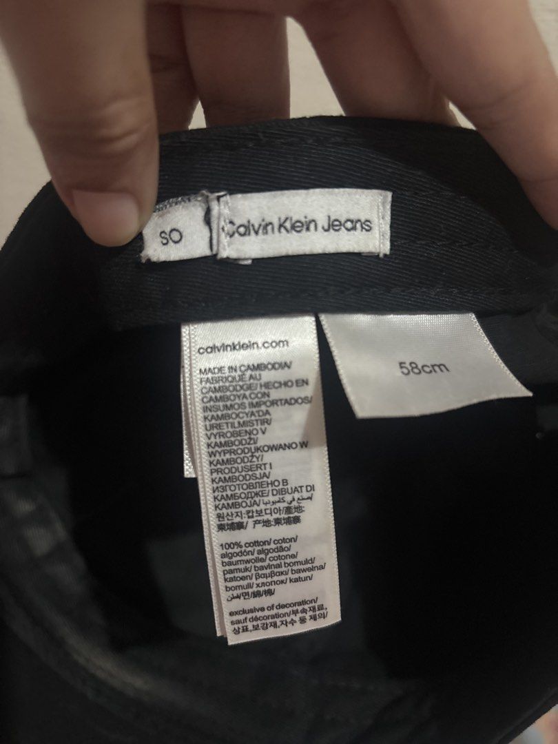Calvin Klein Jeans Black Baseball Cap (Category: Caps & Hats) located in Taguig. Submitted by fatzy24 (Listing ID 1468920840, Image 3). Description: Black Calvin Klein Jeans cap with embroidered white CK logo on the front. Made of 100% cotton, 58cm sizing. Silver-tone metal buckle closure stamped with CK branding at the back. Interior tags intact showing fabrication details from Cambodia..