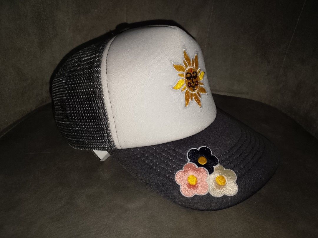 Celestial Sun & Floral Embroidered Trucker Hat (Grey/White) (Category: Hats & Beanies) located in Binangonan. Submitted by yuristalin888 (Listing ID 1468720595, Image 3). Description: Add a touch of whimsical charm to your everyday look with this stylish trucker hat. Featuring a peaceful embroidered smiling sun face on the white front panel and a trio of colorful floral patches accenting the grey curved brim, this cap blends retro style with a pl