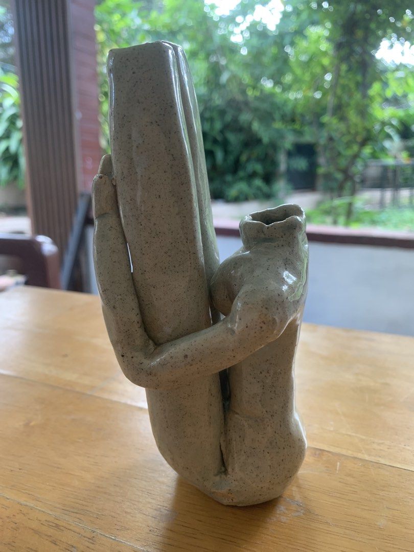 Ceramic Abstract Human Figure Hugging Pillar Vase (Category: Vases & Decorative Bowls) located in Quezon City. Submitted by sojisup (Listing ID 1468714881, Image 3). Description: - Unique handmade ceramic vase shaped like human figures hugging a central pillar - Beautiful speckled beige glaze with a glossy finish - Heavy clay build that sits flat and stable on wooden surfaces - Perfect for holding small stems or displaying as a standalone art pie