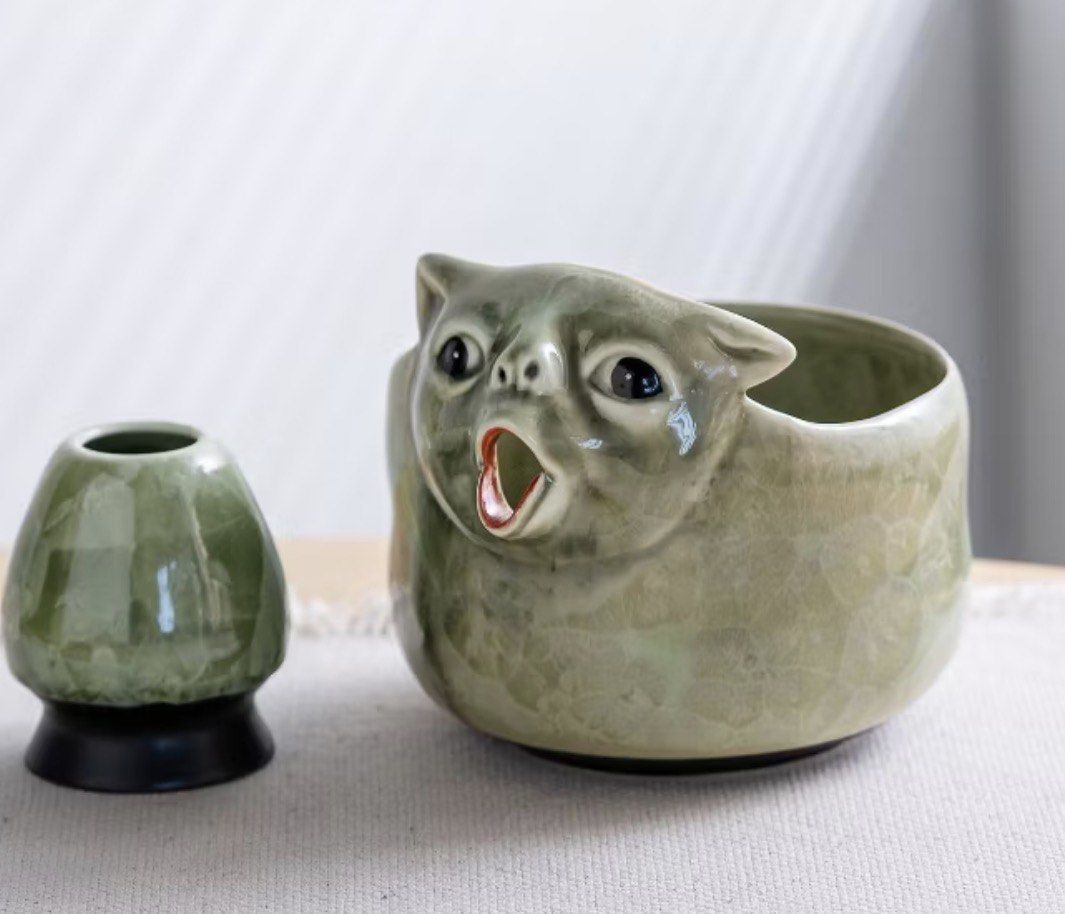 Ceramic green meme cat chawan (matcha bowl) (Category: Coffee & Tea Tableware) located in Mandaluyong City. Submitted by sandylingling94 (Listing ID 1468715319, Image 1). Description: - Adorable cat-shaped ceramic matcha bowl with soft green glaze and dark speckles - Designed with wide eyes and an open mouth that doubles as a convenient pouring spout - Used only twice, for video taking Rfs: buying a different chawan Can meet up at any MRT Station