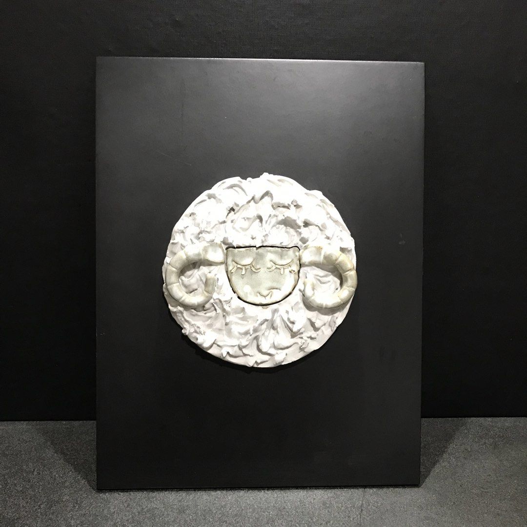 Ceramic sheep wall art sculpture mounted on black board (Category: Wall Decor) located in Baao. Submitted by all.things.japan (Listing ID 1468747832, Image 1). Description: 13.5 x 10.25 inches - Handmade ceramic sleeping sheep sculpture - Features textured white wool and curled horns - Securely mounted on a rectangular black board with a blue hanging cord - Unique art piece, perfect for home decor - Excellent, clean condition ready for display.