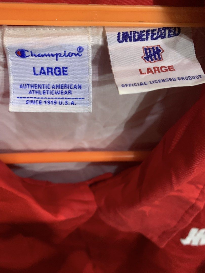 Champion x Undefeated Red Coach Jacket Large (Category: Coats, Jackets and Outerwear) located in Marawi City. Submitted by biidnillah (Listing ID 1468820176, Image 3). Description: - Brand: Champion x Undefeated - Item: Coaches Jacket - Color: Red - Size: Large - Design: Button-up front, collar, front pockets, white Undefeated chest logo - Back Detail: Large embroidered UNDEFTD text patch in orange and white - Interior: Clean inner lining with of
