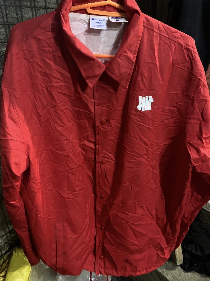Champion x Undefeated Red Coach Jacket Large (Category: Coats, Jackets and Outerwear) located in Marawi City. Submitted by biidnillah (Listing ID 1468820176, Image 1). Description: - Brand: Champion x Undefeated - Item: Coaches Jacket - Color: Red - Size: Large - Design: Button-up front, collar, front pockets, white Undefeated chest logo - Back Detail: Large embroidered UNDEFTD text patch in orange and white - Interior: Clean inner lining with of