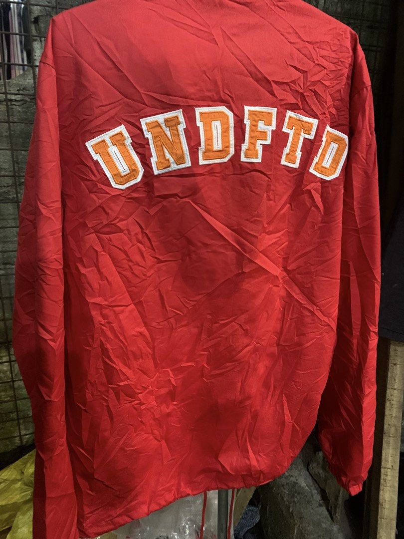 Champion x Undefeated Red Coach Jacket Large (Category: Coats, Jackets and Outerwear) located in Marawi City. Submitted by biidnillah (Listing ID 1468820176, Image 2). Description: - Brand: Champion x Undefeated - Item: Coaches Jacket - Color: Red - Size: Large - Design: Button-up front, collar, front pockets, white Undefeated chest logo - Back Detail: Large embroidered UNDEFTD text patch in orange and white - Interior: Clean inner lining with of