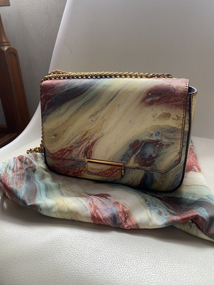 Charles & Keith Marble Print Chain Shoulder Bag (Category: Shoulder Bags) located in Marikina City. Submitted by patsnessss29 (Listing ID 1468728562, Image 1). Description: - Brand: Charles & Keith - Design: Unique marble paint print with structured silhouette and clean stitching - Hardware: Gold-tone chain strap and matching metallic clasp with engraved branding - Closure: Flap front design - Included: Matching printed dust bag - Usage: Compact 