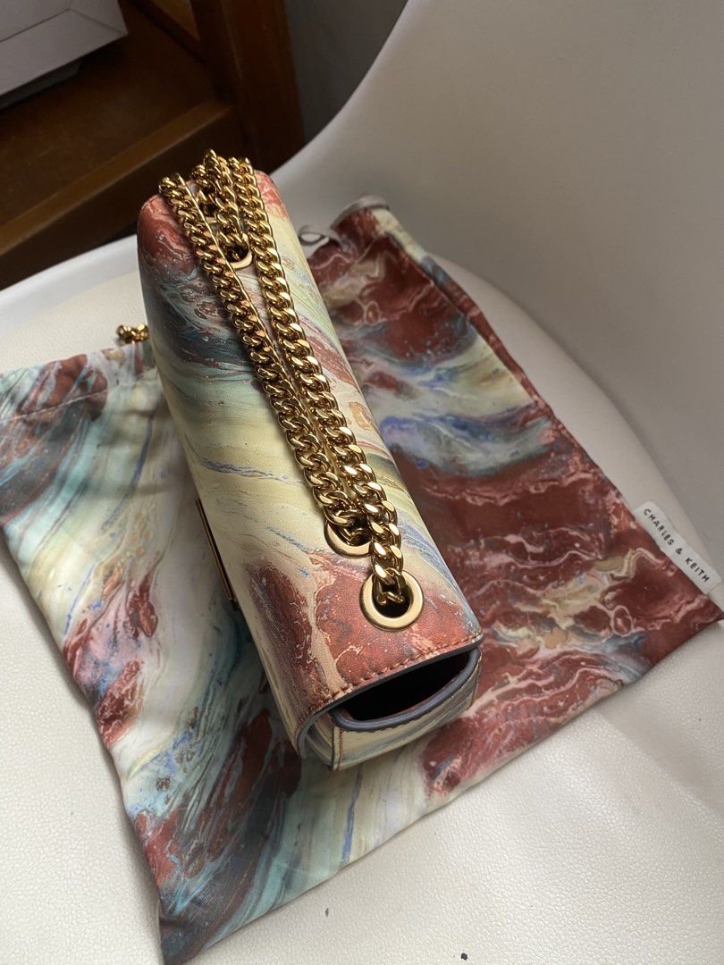 Charles & Keith Marble Print Chain Shoulder Bag (Category: Shoulder Bags) located in Marikina City. Submitted by patsnessss29 (Listing ID 1468728562, Image 3). Description: - Brand: Charles & Keith - Design: Unique marble paint print with structured silhouette and clean stitching - Hardware: Gold-tone chain strap and matching metallic clasp with engraved branding - Closure: Flap front design - Included: Matching printed dust bag - Usage: Compact 