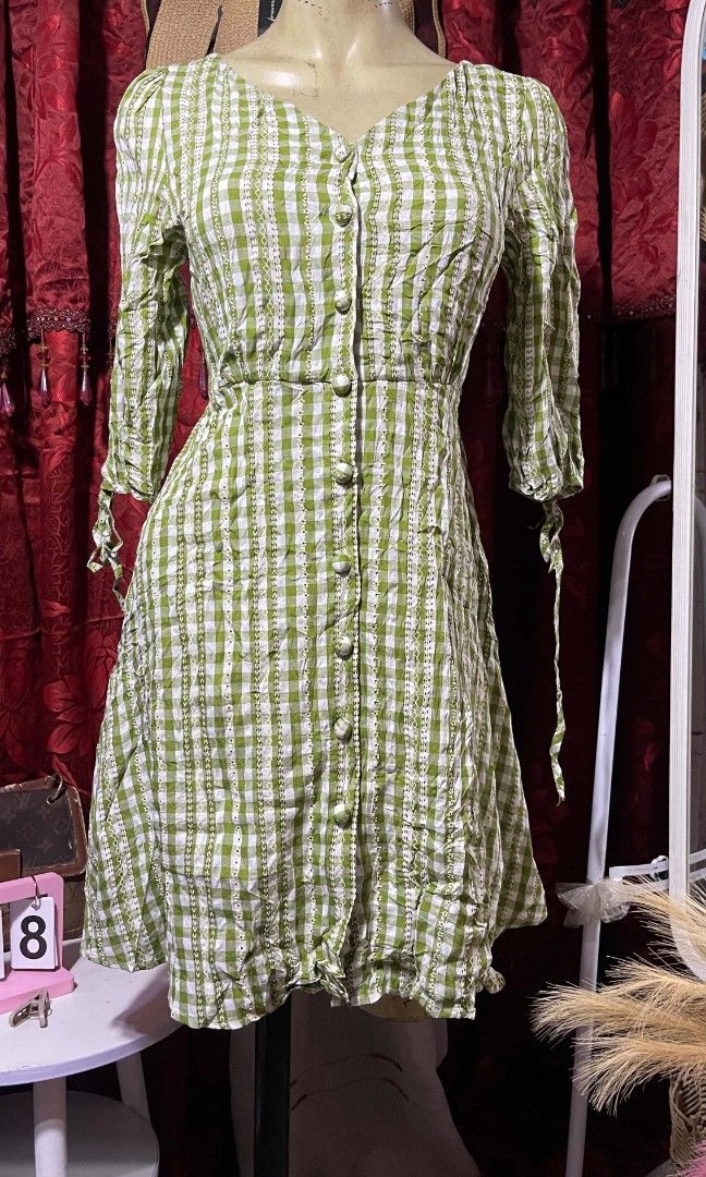 Chekered green mini dress (Category: Dresses) located in Manila. Submitted by wheneity67thifted (Listing ID 1468928071, Image 1). Description: This is a light green and white gingham check button-down dress featuring a V-neckline, three-quarter sleeves with tie cuffs, and an empire waistlin.