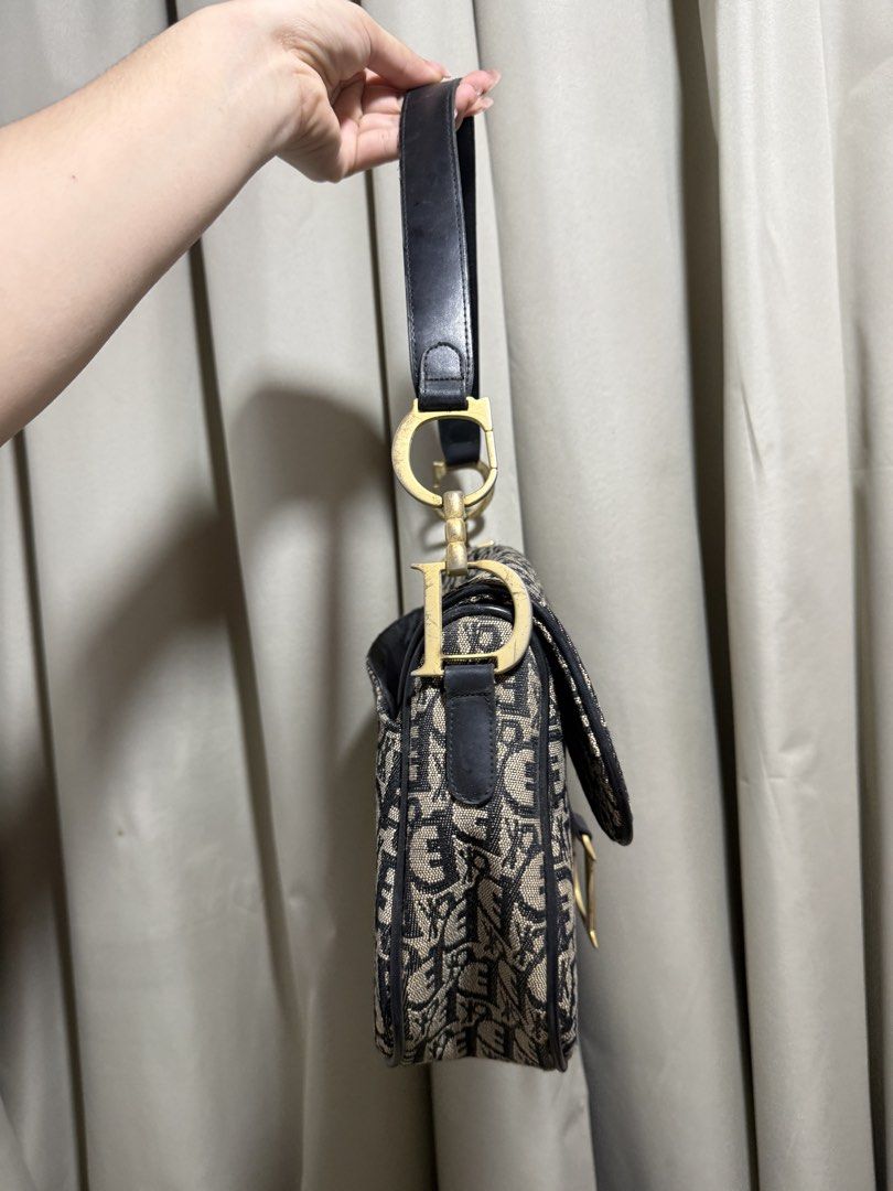 Christian Dior Oblique Saddle Bag (Category: Luxury Bags & Wallets) located in Abucay. Submitted by fastlion.584bdf (Listing ID 1468892662, Image 3). Description: - Brand: Christian Dior - Style: Iconic Saddle Bag - Material: Classic blue oblique canvas with black leather trim - Hardware: Aged gold-tone with signature D stirrup clasp and CD strap rings - Closure: Top zip closure - Interior: Fabric-lined with enough space for daily essentials - Mo