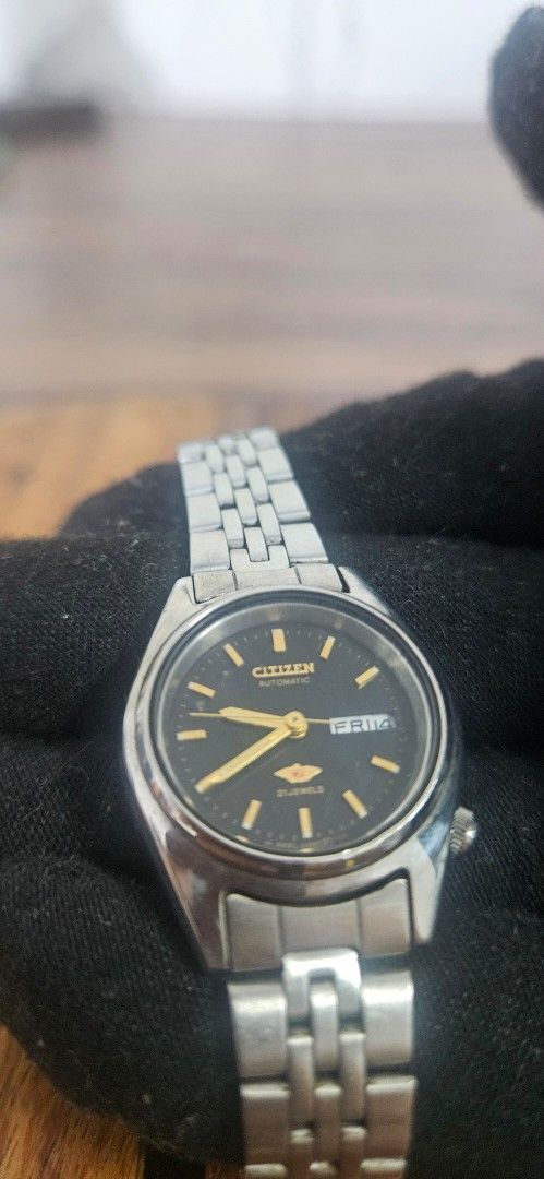 Citizen Automatic 21 Jewels Black Dial Watch (Category: Women's Watches) located in Santa Maria. Submitted by rommelmateo (Listing ID 1468863171, Image 1). Description: - Movement: Automatic with 21 jewels - Dial: Classic black with gold-tone hands and markers - Features: Day-date window at 3 o'clock - Build: Stainless steel case and matching metal link bracelet - Closure: Branded clasp - Crown: Positioned on the right side needs cleaning.