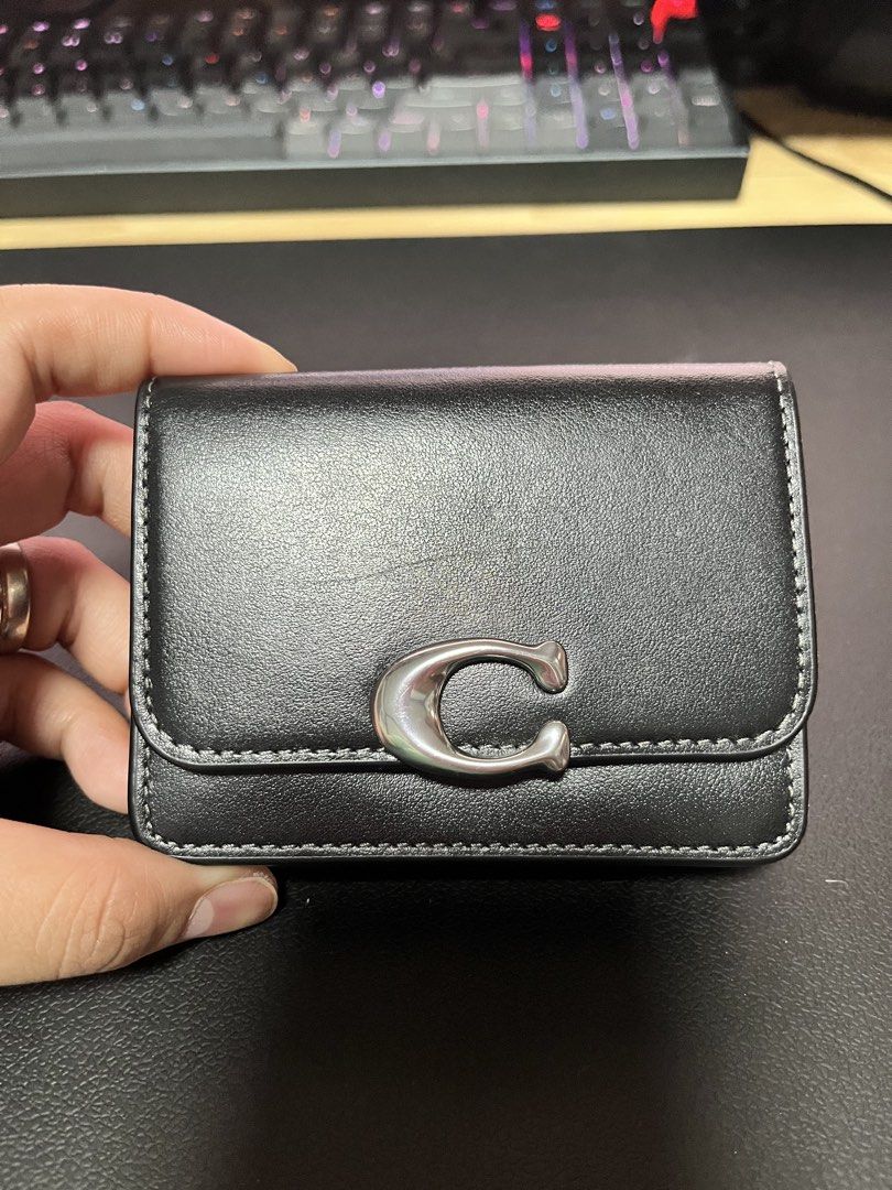 Coach Black Genuine Leather Wallet with Silver C Logo (Category: Wallets & Card holders) located in San Jose. Submitted by roxehfoxeh (Listing ID 1468802264, Image 1). Description: - Material: Genuine leather - Hardware: Silver-tone signature C on front flap - Design: Compact tri-fold style with contrast white stitching - Size: Everyday pocket-sized for convenience.