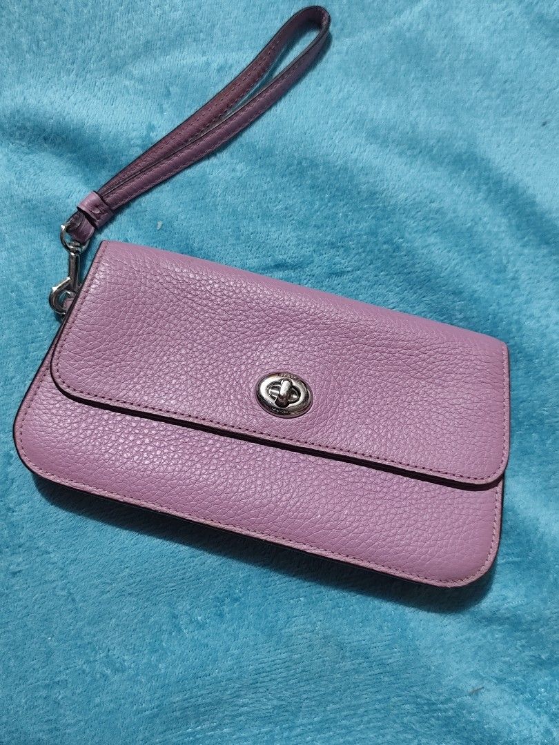 Coach Purple Pebble Leather Wristlet (Category: Luxury Bags & Wallets) located in Manila. Submitted by k.cariaa (Listing ID 1468756547, Image 1). Description: - Brand: Coach - Material: Textured pebble leather - Color: Light purple / lilac - Hardware: Silver-tone with engraved 'Coach New York' turnlock - Features: Detachable wrist strap, secure turnlock closure, compact size for cards and cash - Flaw Notice: Visible blue ink stains on the back po