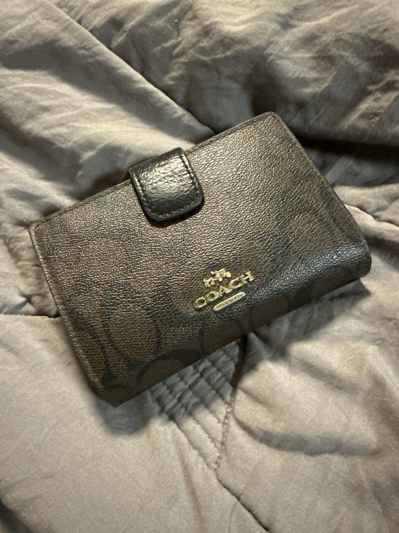Coach Signature Brown Medium Snap Wallet (Category: Luxury Bags & Wallets) located in Caloocan City. Submitted by tootsief (Listing ID 1468878008, Image 1). Description: - Authentic Coach medium bi-fold wallet - Classic brown signature monogram canvas with gold-tone hardware - Front snap closure tab with Coach New York lettering - Multiple card slots and cash compartments inside - Compact and sturdy design, perfect for everyday use - Fits easily 