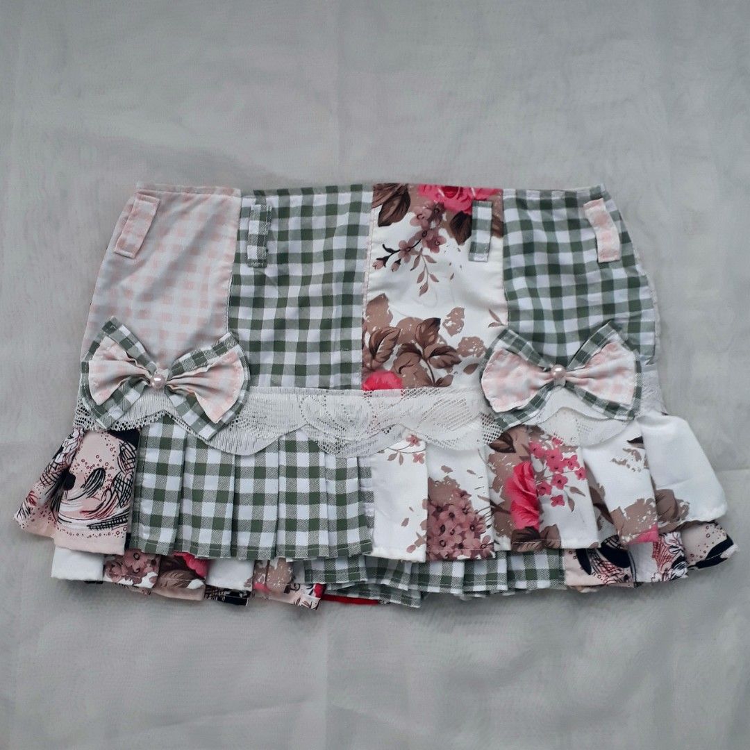 Cottagecore Patchwork Pleated Mini Skirt (Category: Skirts) located in Cabanatuan. Submitted by madeby_csnstudio (Listing ID 1468728487, Image 2). Description: MEASUREMENTS: Waist: 30 inches (76.2 cm) Hips: 37 inches (93.98 cm) Length: 13 inches (33.02 cm) DETAILS: The multi-fabric layout features a combination of sage gingham checks, delicate pink gingham, vintage rose floral prints, and subtle graphic accents. Built-in belt loops outline the wa