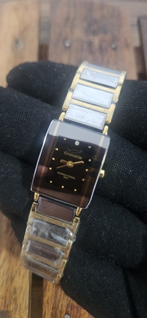 Crocodile International gold tone rectangle watch (Category: Women's Watches) located in Santa Maria. Submitted by rommelmateo (Listing ID 1468859619, Image 1). Description: - Brand: Crocodile International - Style: Gold-tone watch with a sleek rectangular dark dial and gold hands - Case: Gold case with elegant curved sides - Strap: Bracelet strap with alternating links, still wrapped in original protective plastic - Closure: Secure fold-over cla