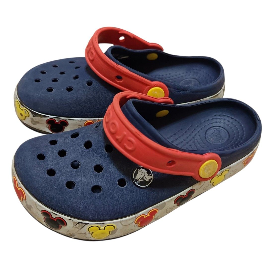 Crocs Mickey Mouse Kids Clogs Size 13 (Category: Babies & Kids Fashion) located in Nasugbu. Submitted by staffpicks1515 (Listing ID 1468792608, Image 2). Description: - Brand: Crocs - Size: Kids 13 - Color: Navy blue with red heel straps and yellow pivots - Design: Fun Disney Mickey Mouse graphic strip around the soles - Origin: Made in China - Condition: Normal signs of wear on soles and upper, still very functional and fun to wear.