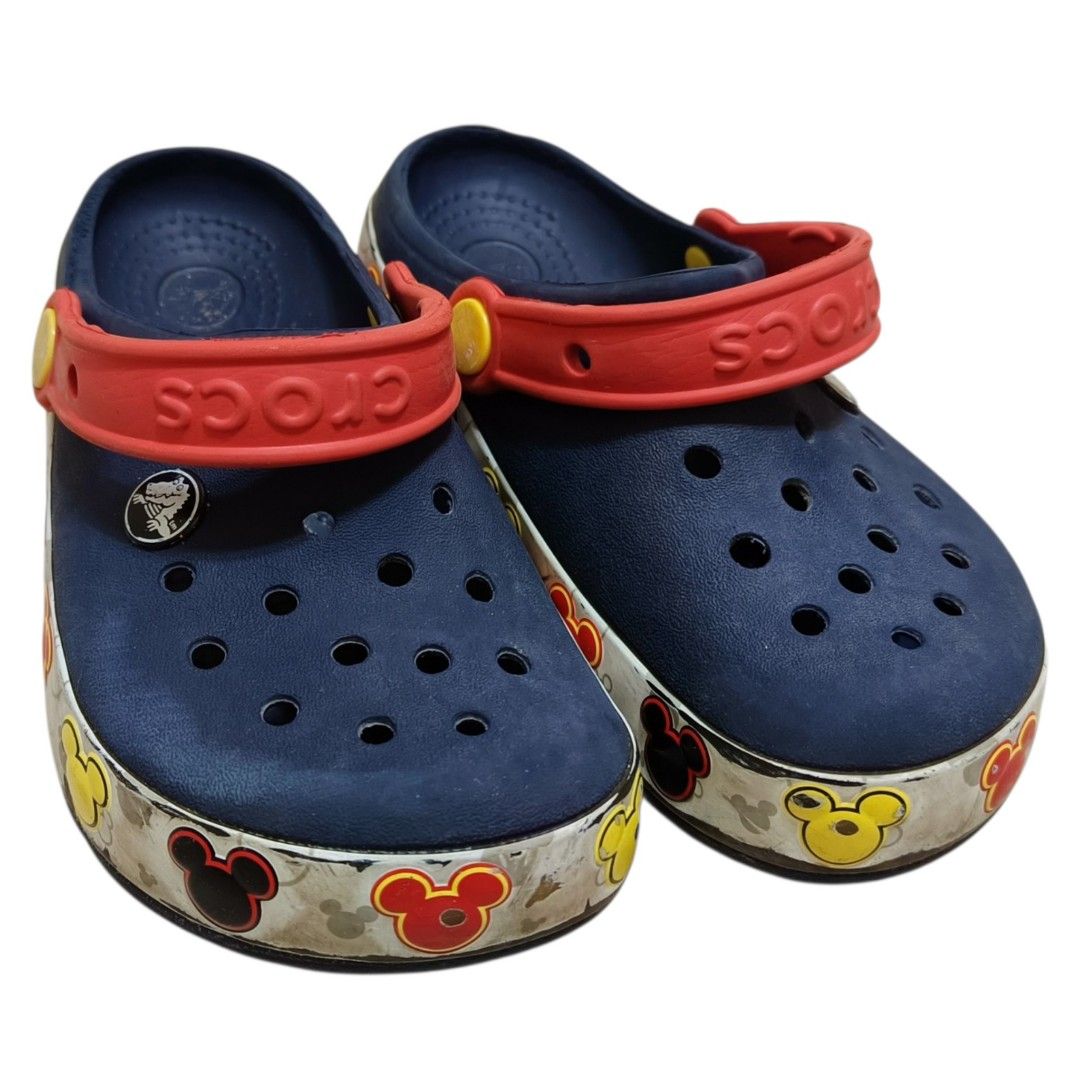 Crocs Mickey Mouse Kids Clogs Size 13 (Category: Babies & Kids Fashion) located in Nasugbu. Submitted by staffpicks1515 (Listing ID 1468792608, Image 3). Description: - Brand: Crocs - Size: Kids 13 - Color: Navy blue with red heel straps and yellow pivots - Design: Fun Disney Mickey Mouse graphic strip around the soles - Origin: Made in China - Condition: Normal signs of wear on soles and upper, still very functional and fun to wear.