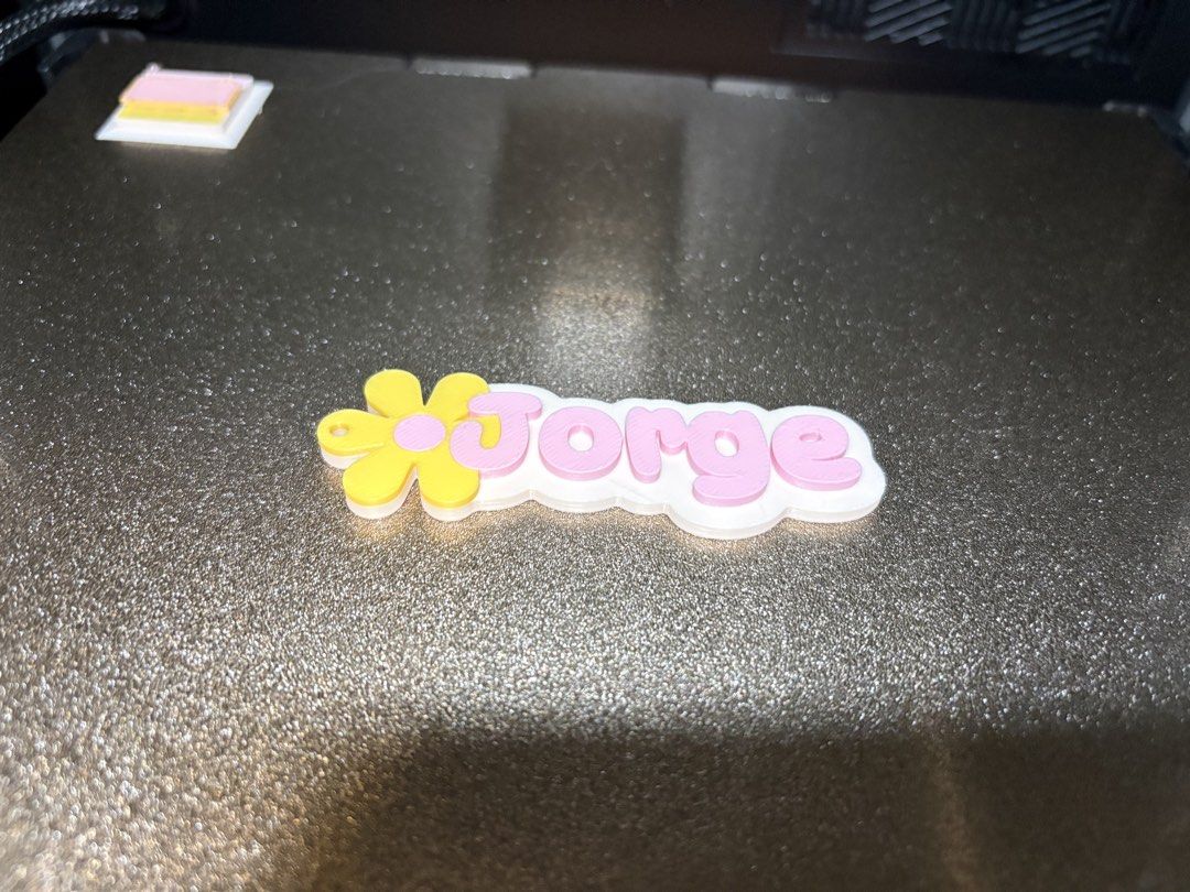Custom 3D Printed Flower Name Keychain (Category: Handmade Craft) located in Paranaque City. Submitted by sqt_closet (Listing ID 1468736115, Image 2). Description: - Custom name keychain - White base with playful pink bubble letters - Adorned with a yellow flower (pink center) on the left side 1pc for P45 each 5pcs for 210 10pcs 400.