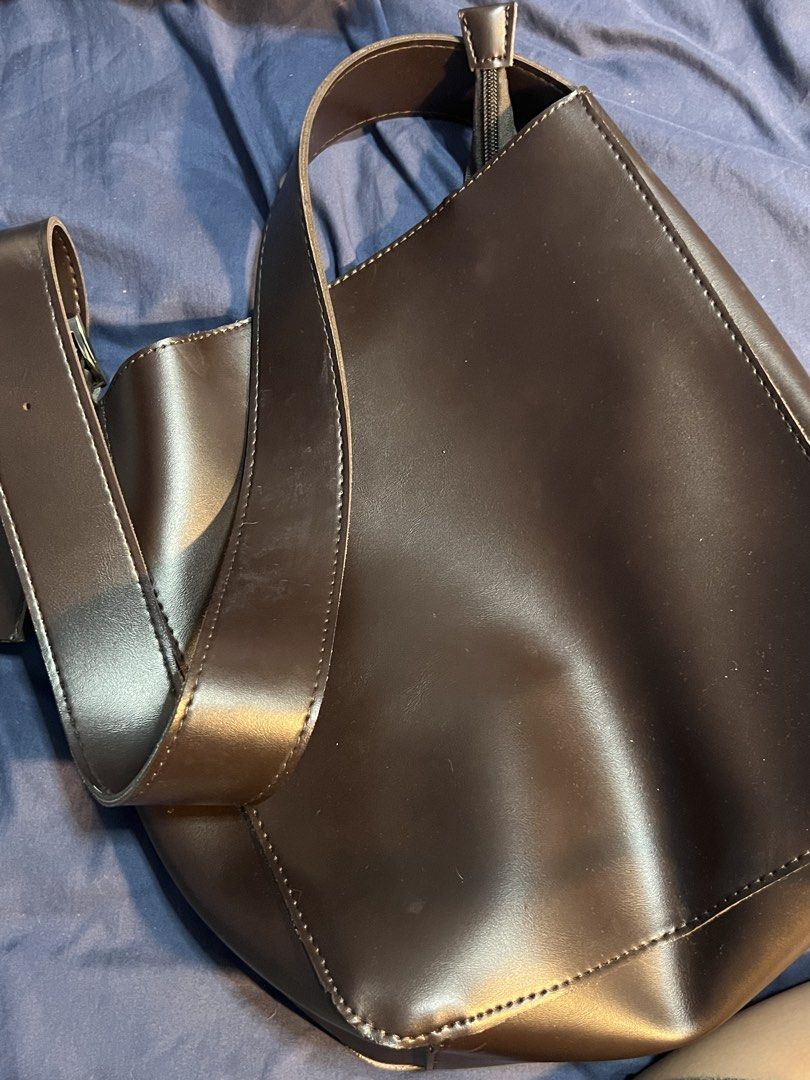 Dark Brown Leather Bucket Shoulder Bag (Category: Shoulder Bags) located in Marikina City. Submitted by yssacee (Listing ID 1468914801, Image 2). Description: - Color & Material: Dark brown faux leather with silver-tone buckle - Closure & Interior: Secure zippered top with a spacious, unlined raw interior - Strap: Adjustable for a customized fit - Style: Minimalist design, ideal for everyday use - Condition: Brand new with minor dust specs from s