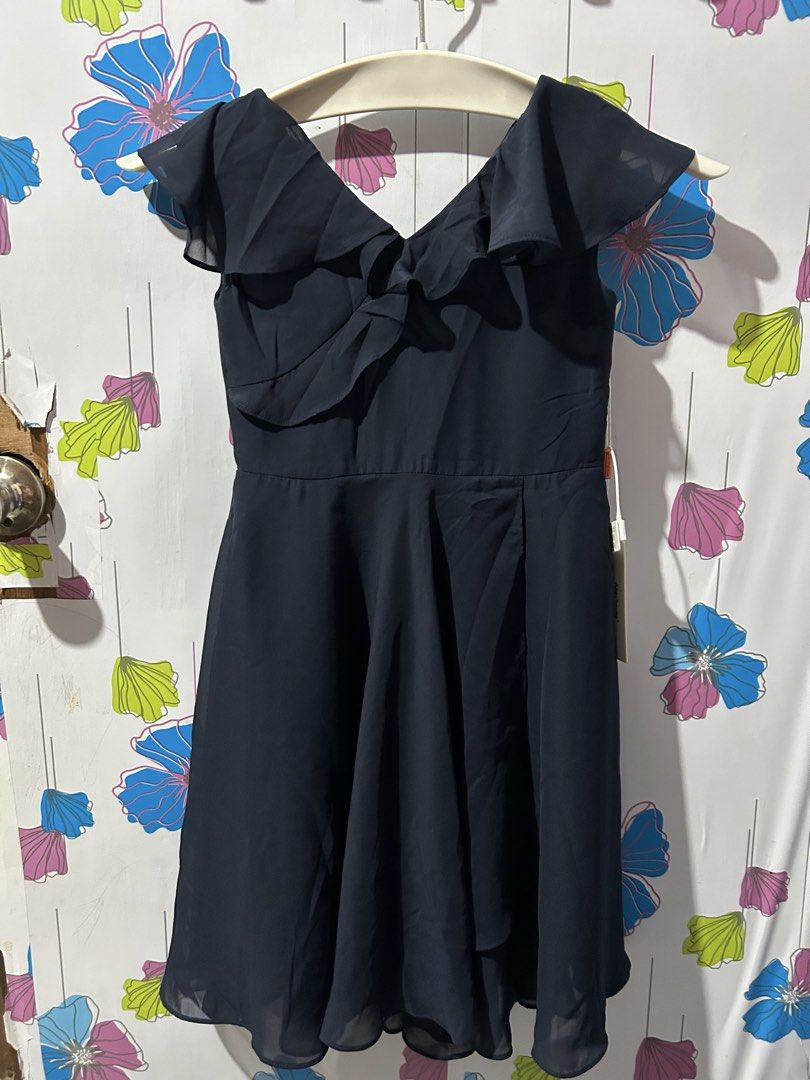 Dark Navy Blue Ruffle V-Neck Dress (Category: Babies & Kids Fashion) located in San Jose. Submitted by coolbear-85a9de (Listing ID 1468714549, Image 2). Description: - Color: Dark navy blue - Style: Ruffled V-neck, short flutter sleeves, flared midi-length skirt - Condition: Brand new with original tags attached, clean and ready to wear - Details: Lightweight chiffon-like fabric, fully lined, back zipper closure - Versatility: Simple and classic,