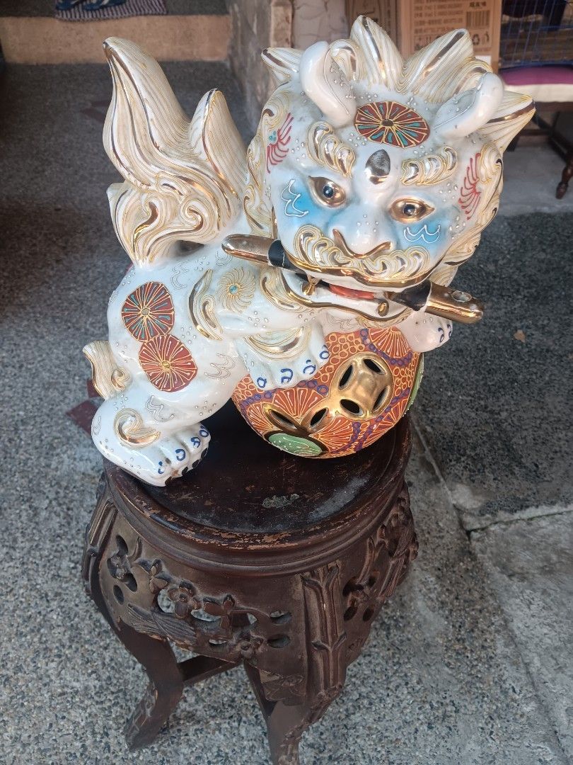 Decorative Ceramic Foo Dog Statue with Stand (Category: Figurines & Statues) located in Las Pinas. Submitted by jesus1smysavi0r (Listing ID 1468738800, Image 2). Description: - Type: Traditional Asian ceramic foo dog decor - Design: Foo dog holding a sword, perched on an ornate ball - Details: Hand-painted in blue, red, gold, and turquoise with raised gold linework on the tail and mane - Stand: Includes a carved dark wood tall display stand with 