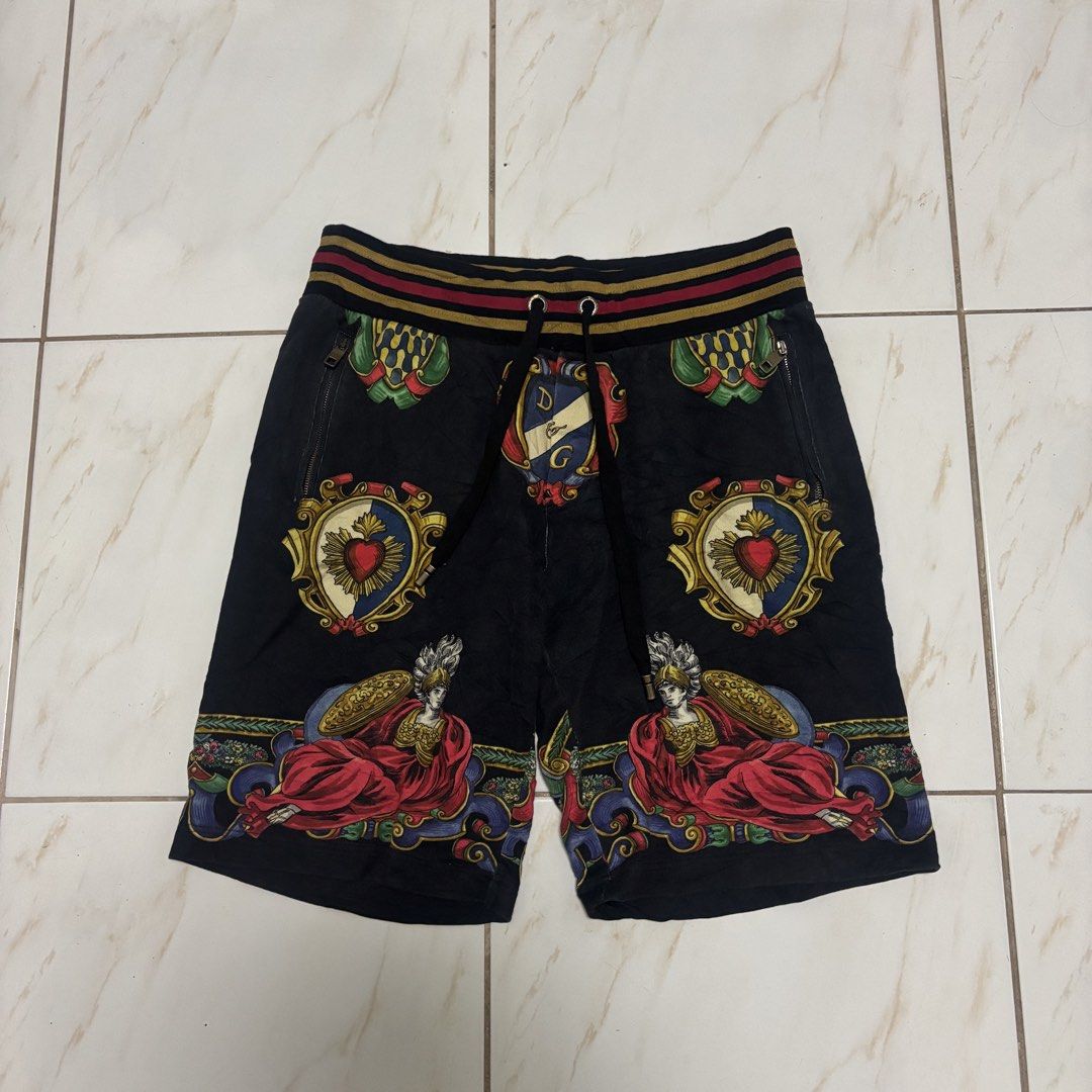 D&g short (Category: Shorts) located in San Fernando. Submitted by diff.thr1ft (Listing ID 1468864591, Image 1). Description: - Brand: D&G - Color: Black with multi-color baroque graphic print (crests and classical figures) - Waistband: Elastic striped waistband with adjustable drawstring and branded metal aglets - Pockets: Secure zippered side pockets with engraved Dolce & Gabbana zipper pulls - Style: Statement streetwear/casual luxury short Cu