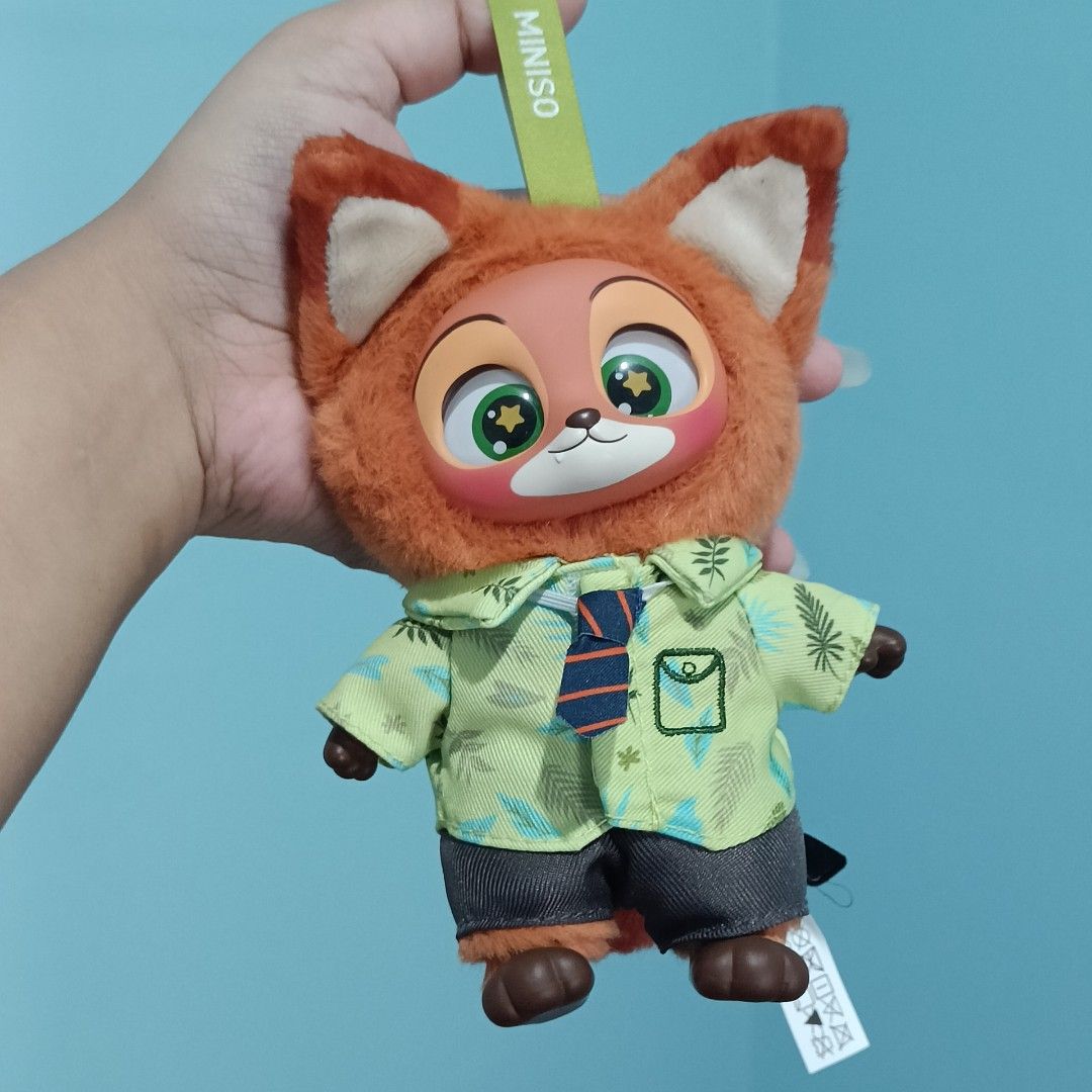 Disney Miniso Zootopia Nick Wilde Plush Keychain (Category: Plushies & Soft Toys) located in Baguio. Submitted by baileybails (Listing ID 1468754667, Image 1). Description: - Authentic Disney Miniso Nick Wilde plush keychain - Wears a green tropical shirt, blue striped tie, and grey shorts - Features cute green eyes with star highlights - Includes original Miniso hanging strap and side fabric tags - Clean fabric with bright, vibrant colors - Perf