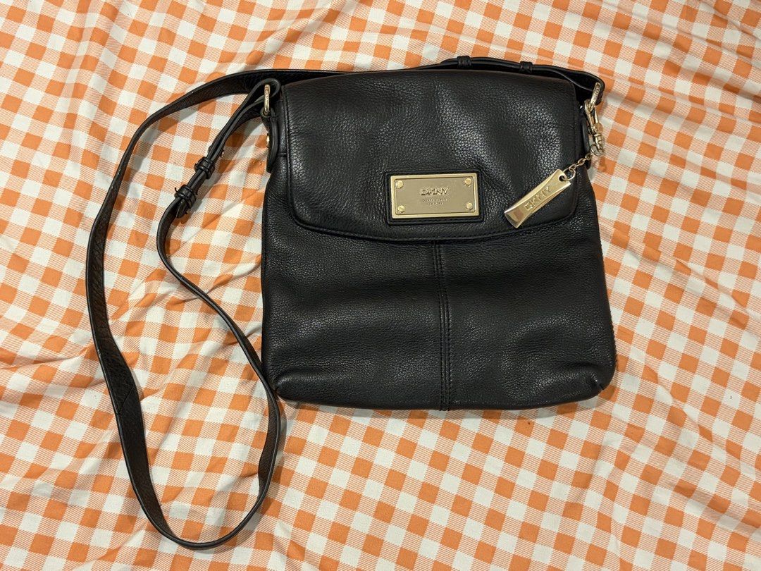 DKNY Donna Karan Purse (Category: Luxury Bags & Wallets) located in Manila. Submitted by jdace (Listing ID 1468845721, Image 1). Description: - 100% genuine black leather with a clean pebble grain texture - Elegant gold-tone hardware including a front rectangular logo plaque and side metal charm - Structured everyday design with stylish vertical seam detailing - Comfortable, adjustable thin black leather shoulder strap - Trusted seller with great