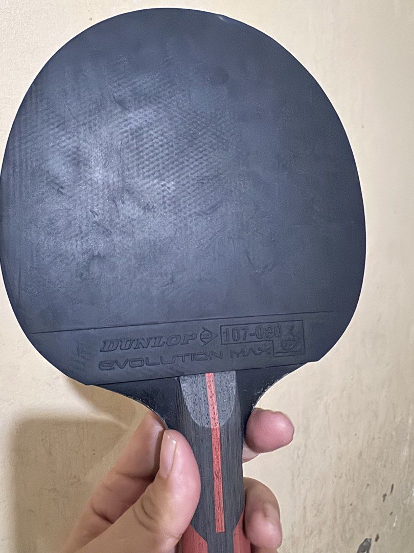 Dunlop Evolution Max 3000 Table Tennis Bat with Cover (Category: Racket and Ball Sports) located in Angeles City. Submitted by thala.1204.68 (Listing ID 1468827594, Image 2). Description: - Brand/Model: Dunlop Evolution Max 3000 table tennis bat - Condition: Used with minor wear on the red and black rubber surfaces - Handle: Wooden handle featuring a black and red grip design - Inclusion: Comes with the original black Dunlop protective carry case