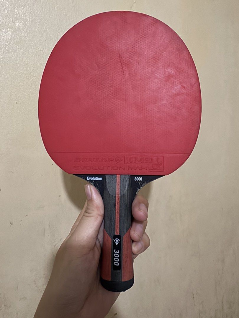Dunlop Evolution Max 3000 Table Tennis Bat with Cover (Category: Racket and Ball Sports) located in Angeles City. Submitted by thala.1204.68 (Listing ID 1468827594, Image 1). Description: - Brand/Model: Dunlop Evolution Max 3000 table tennis bat - Condition: Used with minor wear on the red and black rubber surfaces - Handle: Wooden handle featuring a black and red grip design - Inclusion: Comes with the original black Dunlop protective carry case
