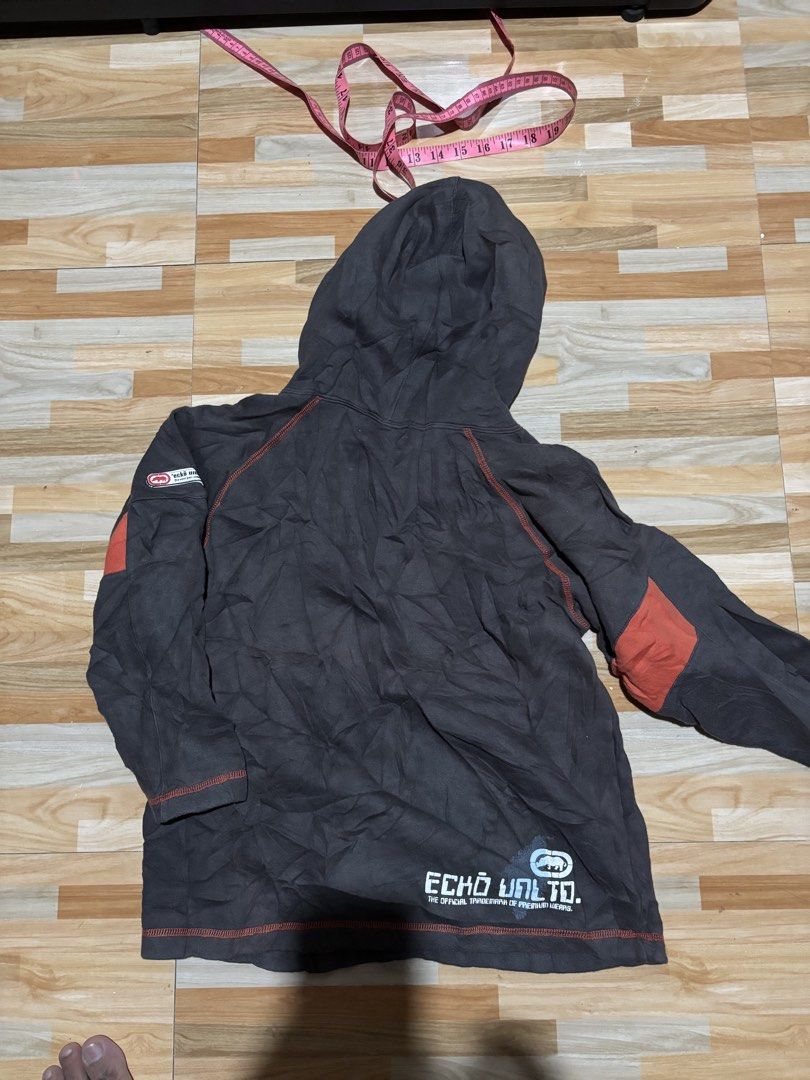 Ecko Unltd. Hooded Sweatshirt Grey Orange Size 140 (Category: Coats, Jackets and Outerwear) located in Tubigon. Submitted by wawiesunbe75372 (Listing ID 1468843365, Image 2). Description: - Brand: Ecko Unltd. - Size: 140 (Kids/Youth) - Color: Grey with vibrant orange accents and yellow drawstrings - Design: Large logo graphics on the chest and back hem - Features: Kangaroo pocket, contrast orange stitching throughout, and ribbed cuffs/hem - Condi