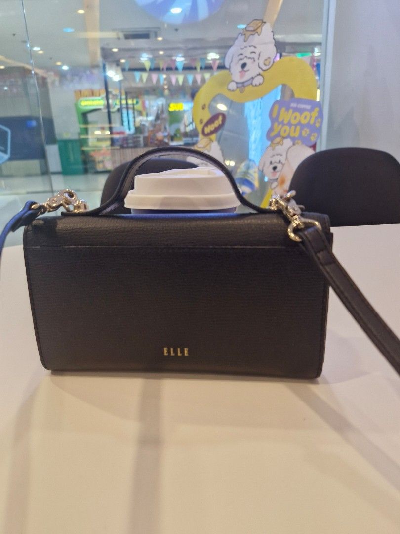 ELLE Black Sling Wallet (Category: Cross-body Bags) located in Las Pinas. Submitted by jmproperties (Listing ID 1468798562, Image 2). Description: - Brand: ELLE - Color: Black with chic gold-tone hardware - Material: Textured leather finish - Versatile carry: Includes a top handle and removable shoulder strap - Interior: Divided compartments, fabric lining, and multiple card slots for easy organization - Condition: Clean inside and out with minim