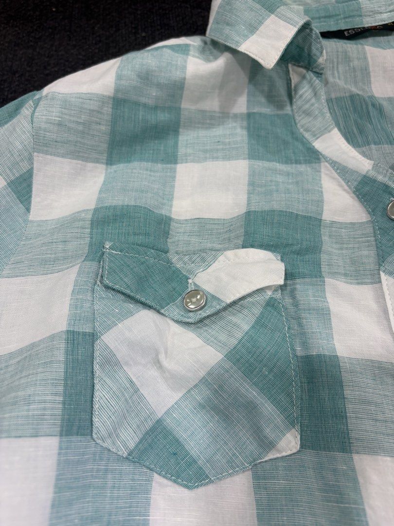 Essenxa Green White Plaid Button Up Shirt XL (Category: Shirts) located in Quezon City. Submitted by fast.closetfinds (Listing ID 1468774792, Image 3). Description: - Brand: Essenxa - Size: XL - Color/Pattern: Green and white check - Design: Long sleeves with metallic snap-button closure - Pockets: Dual chest pockets with button flaps - Fabric: Lightweight and comfortable for casual wear.