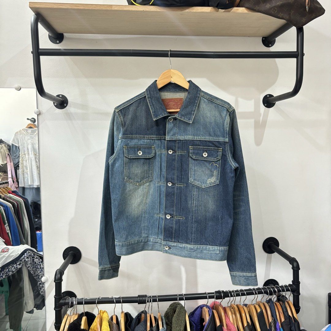 Evisu Selvedege Denim Jacket Blue Size L (Category: Coats, Jackets and Outerwear) located in Bambang. Submitted by heats777 (Listing ID 1468827920, Image 2). Description: - Brand: Evisu - Size: L (indicated on interior leather patch) - Color/Wash: Blue with contrast color block front panels - Pockets: Two chest pockets (one with signature embroidered gull detail) - Hardware: Metal buttons with engraved branding - Design Features: Pleated back det