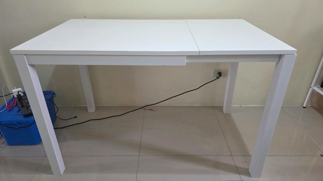 Extendable white dining table (Category: Tables & Sets) located in Makati City. Submitted by maria.valderama (Listing ID 1468881738, Image 2). Description: - White extendable dining table with smooth surface - Sturdy metal frame for daily durability - Ideal for small spaces, apartments, or cozy dining areas - Easy-to-use pull-out leaf panel for extra seating capacity ✨ CONDITION - please see photos to appreciate 📍 LOCATION: EDSA Shaw / Queensrow