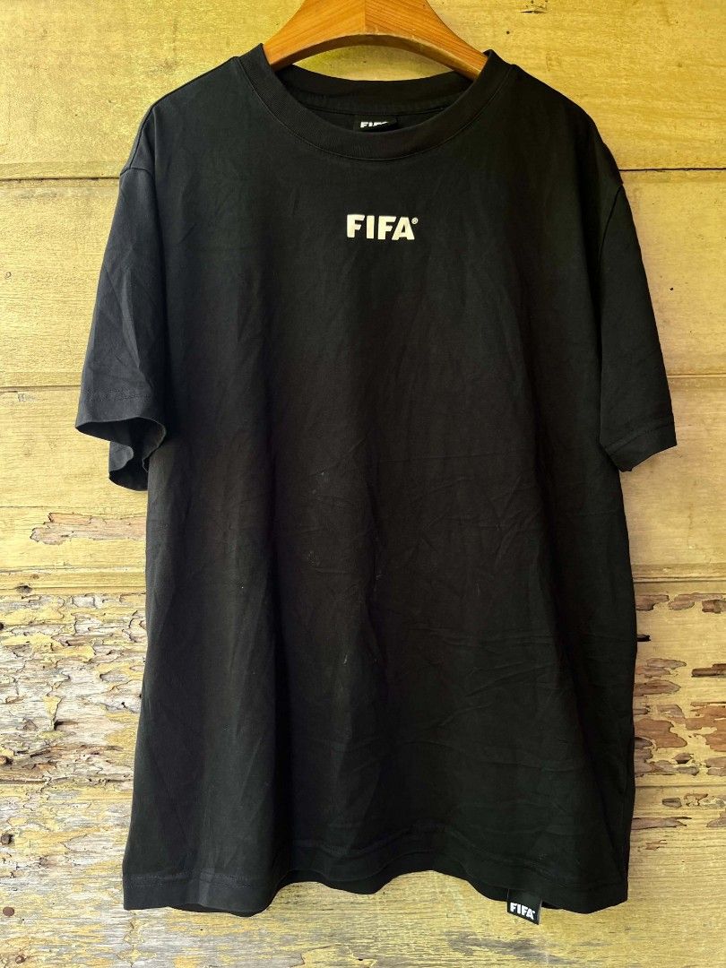 FIFA Black T-Shirt Size M (Category: Tshirts & Polo Shirts ) located in Baroy. Submitted by laudecarlfe24 (Listing ID 1468750132, Image 1). Description: - Item: Official FIFA Football Merchandise T-Shirt - Color: Black with white logo print on chest and back collar - Size: Medium (M) - Measurements: Length 66 cm x Width 51.5 cm - Details: Crew neck, short sleeves, and branded label near the bottom hem - Condition: Excellent, ready to wear.