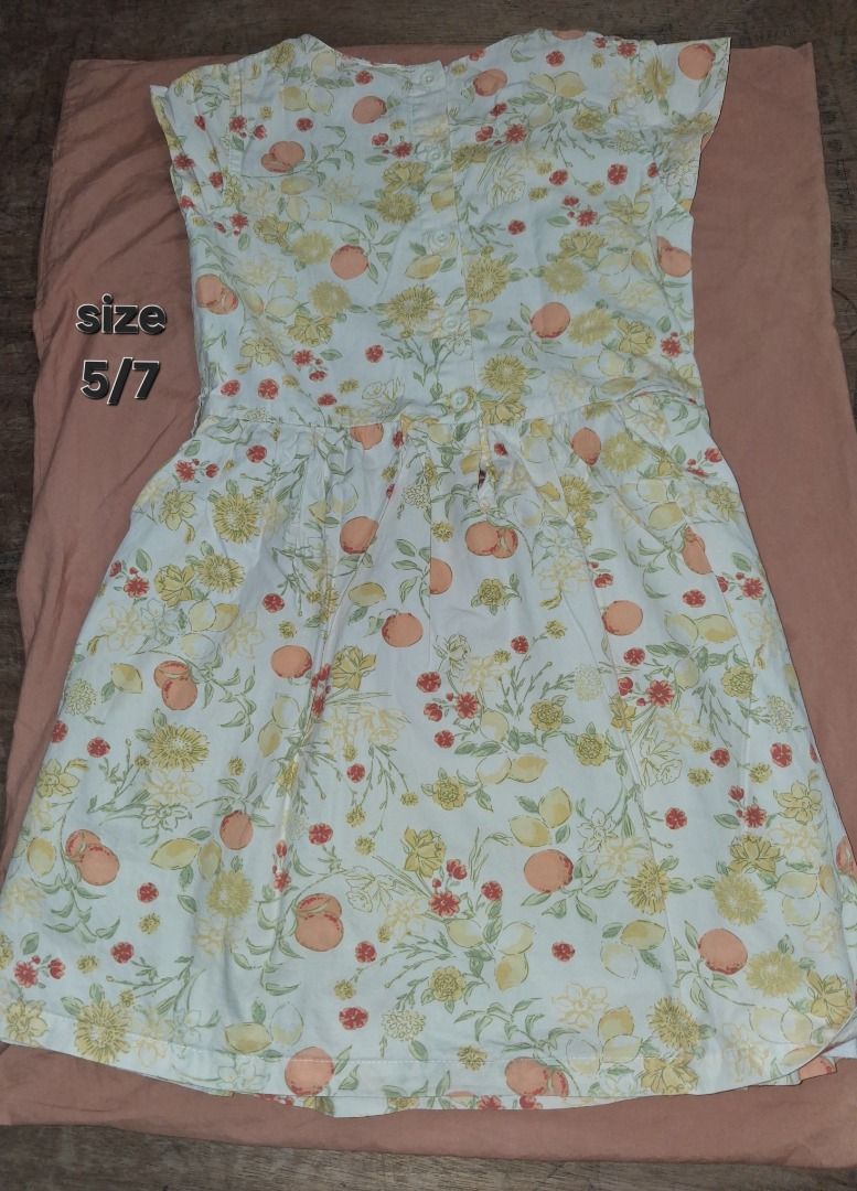 Floral Dress (Category: Babies & Kids Fashion) located in Caloocan City. Submitted by pauline.preloved.stuff (Listing ID 1468752071, Image 1). Description: Super cute white cotton dress featuring a vibrant fruit and floral print. Perfect for warm weather with a fitted bodice, flared pleated skirt, and back button closure. Fits size 5/7..