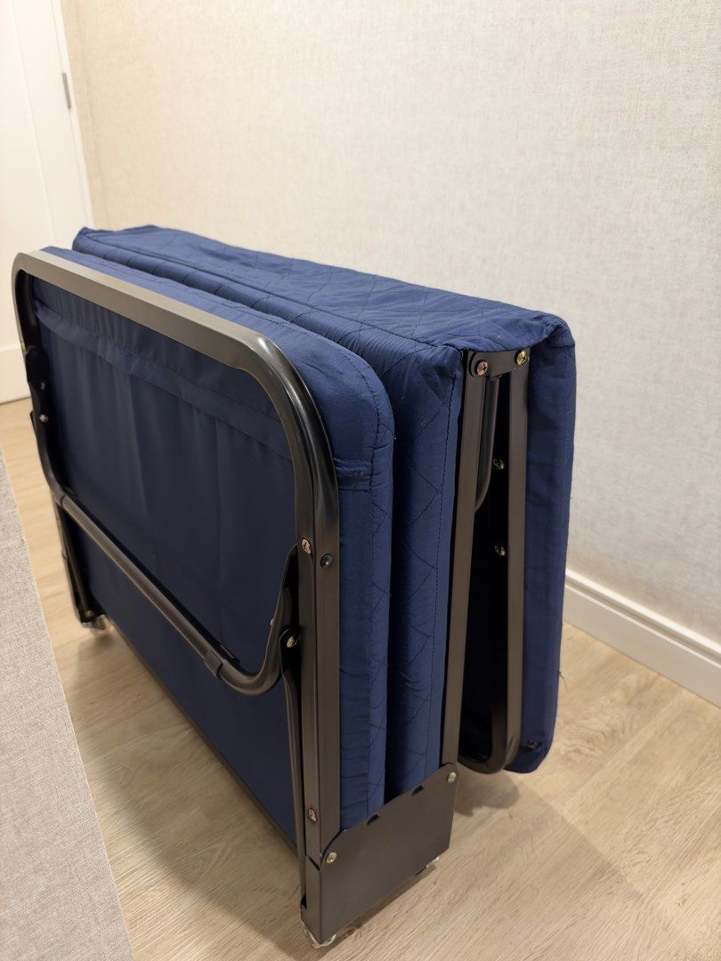 Foldable Single Guest Bed with Mattress and Wheels (Category: Bed Frames & Mattresses) located in Manila. Submitted by lorymingui15824 (Listing ID 1468808971, Image 3). Description: - Color: Navy blue mattress with a sleek black metal frame - Compact & Foldable: Easily folds up for space-saving storage - Portable: Equipped with wheels at the base for effortless moving - Durable: Sturdy build designed for everyday reliability - Ideal Use: Great ex