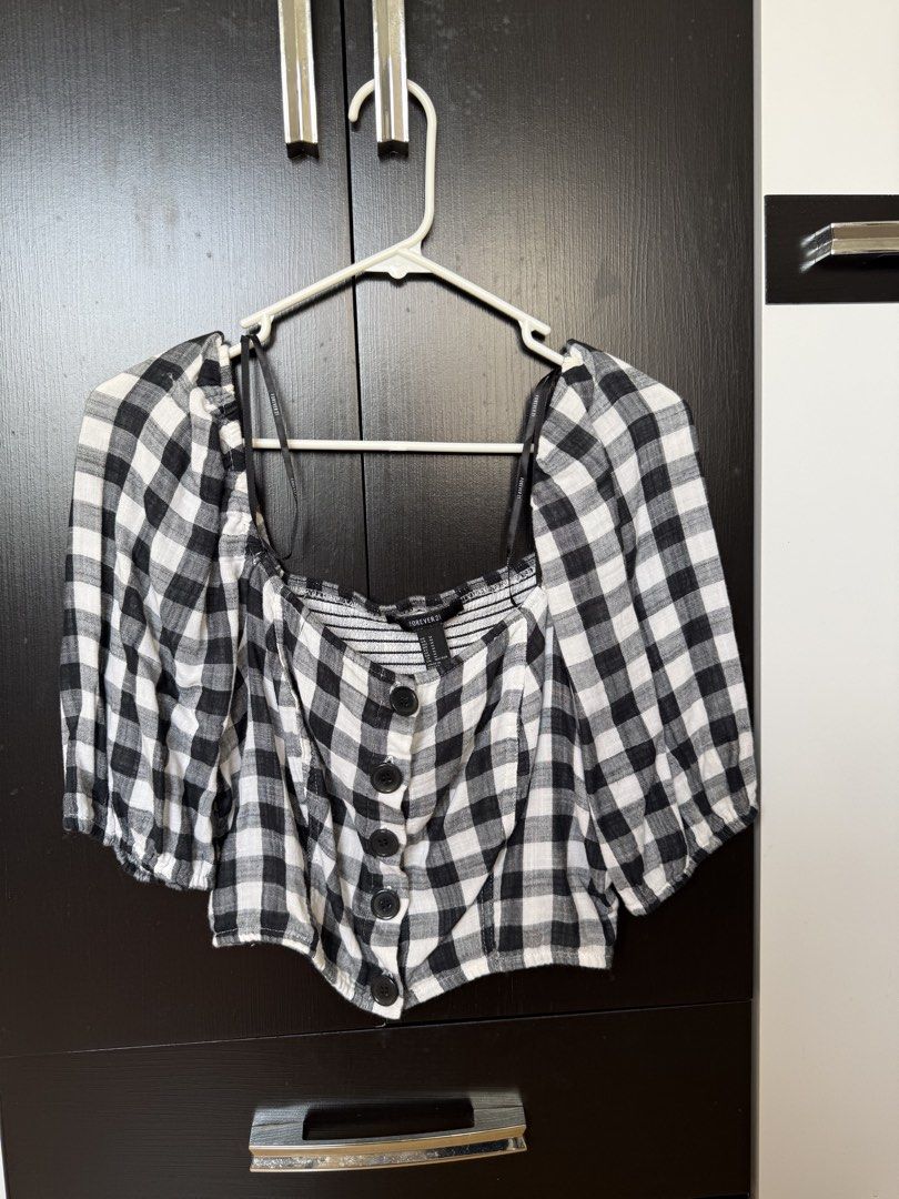 Forever 21 Black and White Gingham Crop Top (Category: Sleeveless) located in Manila. Submitted by caeln (Listing ID 1468762467, Image 2). Description: - Brand: Forever 21 - Size: M - Pattern: Black and white gingham check - Details: Square neckline, puff sleeves, front button closure, and a stretchy smocked back panel - Condition: Worn a few times, washed, and well-kept.