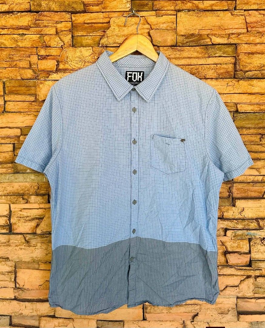 Fox Racing Short Sleeve Button-Up Shirt Checkered Blue (Category: Tshirts & Polo Shirts ) located in Santiago. Submitted by reyibanez253969 (Listing ID 1468801807, Image 1). Description: - Brand: Fox (Irvine, CA) - Large - 22x28.5 - Style: Short sleeve button-up shirt - Design: Light blue upper with grey bottom block, subtle all-over grid pattern - Details: Single chest pocket with tiny Fox logo hardware, branded buttons at front and collar - Mat