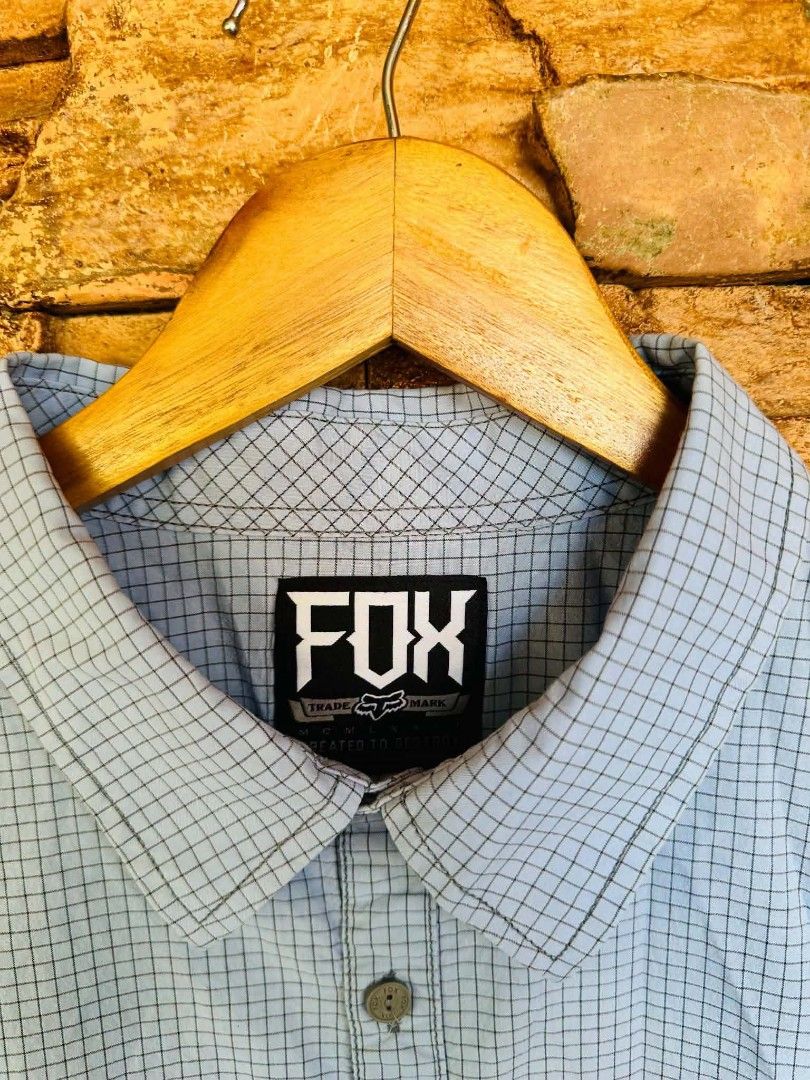 Fox Racing Short Sleeve Button-Up Shirt Checkered Blue (Category: Tshirts & Polo Shirts ) located in Santiago. Submitted by reyibanez253969 (Listing ID 1468801807, Image 2). Description: - Brand: Fox (Irvine, CA) - Large - 22x28.5 - Style: Short sleeve button-up shirt - Design: Light blue upper with grey bottom block, subtle all-over grid pattern - Details: Single chest pocket with tiny Fox logo hardware, branded buttons at front and collar - Mat